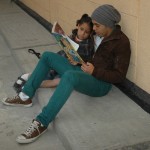 teen and child reading outdoor wall