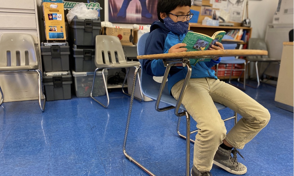 COVID 19 Updates-Student reading his book in class